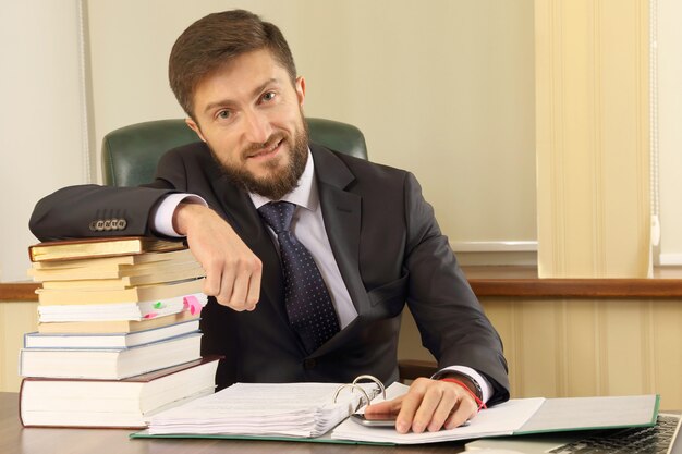 Successful business man in the office with books and documents