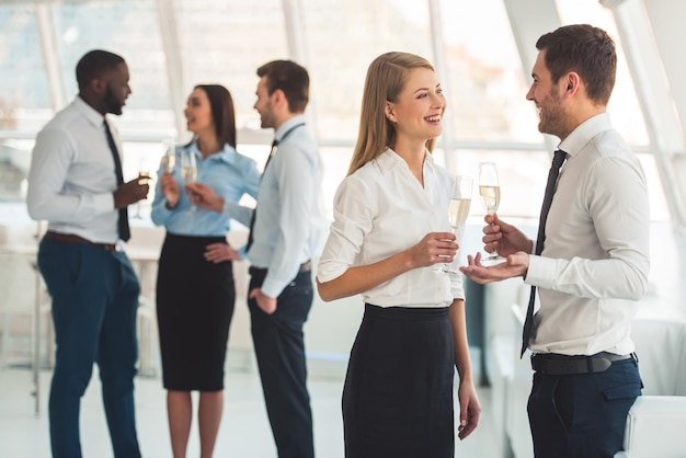 Successful business people are drinking champagne talking and smiling while celebrating in office