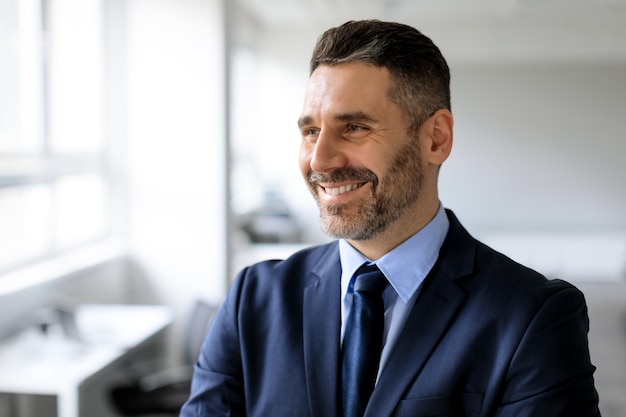 Successful business person Portrait of happy businessman in suit looking aside at free space posing in office