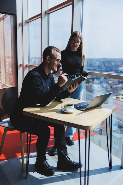 Successful business team male and female colleagues talking at work discussing a new project with a laptop young executives have a friendly conversation cooperate in teamwork in the office