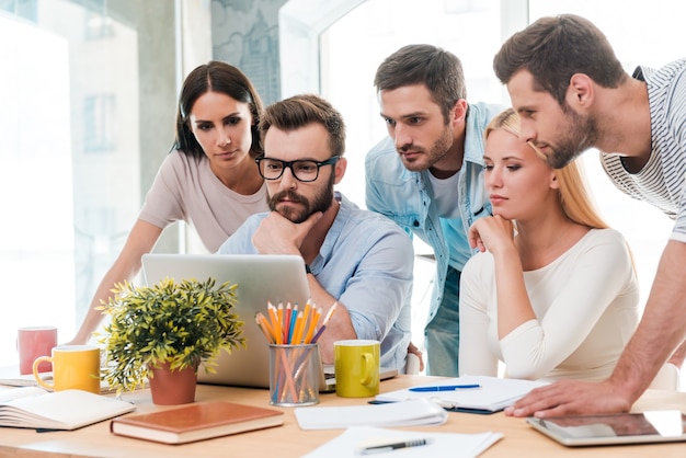 Successful business team at work. Group of confident business people in smart casual wear looking at the laptop together