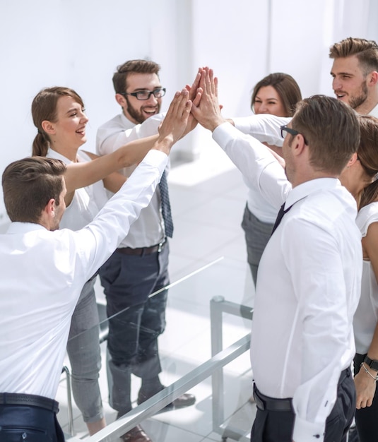 Successful business teams make a high five over their desk