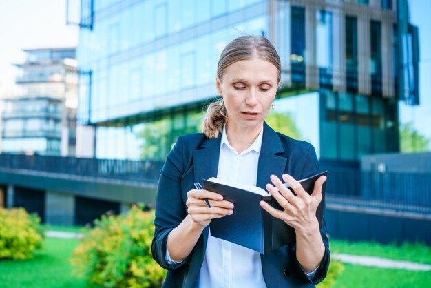 Successful business woman making notes in notebook outdoors in business