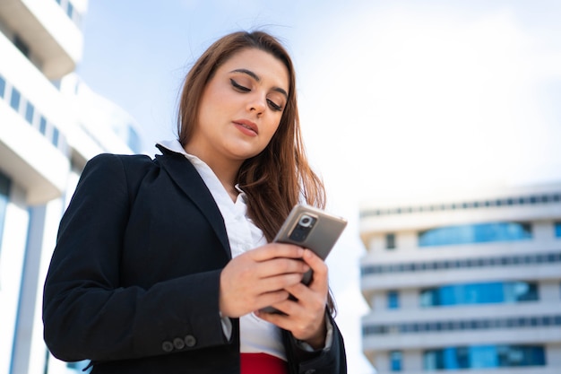 Successful business woman smiling and using the phone dressed in a black suit