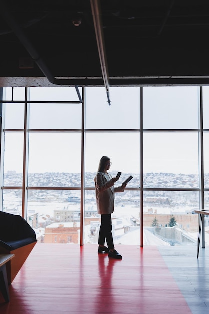 Successful business woman standing looking out the window enjoying the city view confident wealthy leader woman thinking about business success and vision for the future planning new goals