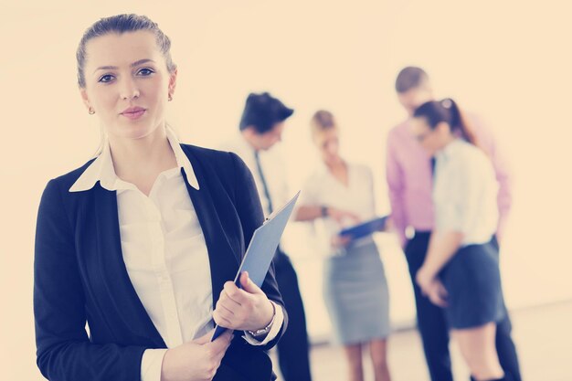 Photo successful business woman standing with her staff in background at modern bright office