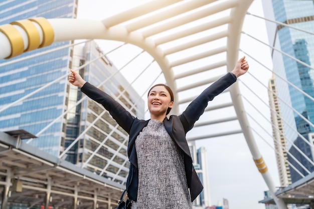 Successful business woman with arms raised in the city