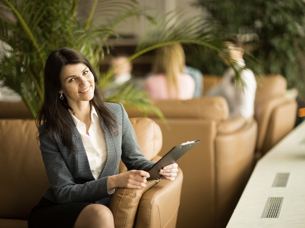 Successful business woman with documents sitting in a chair