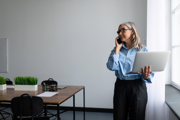 Successful business woman with a laptop in her hands speaks on a mobile phone on the background of