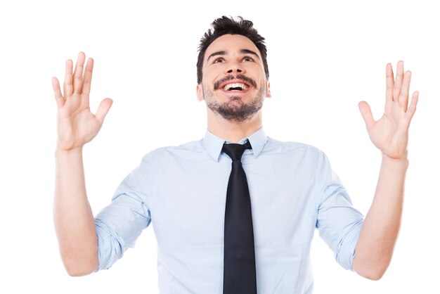 Successful businessman. Happy young man in shirt and tie keeping arms raised and smiling