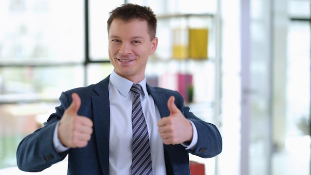 Photo successful businessman in suit showing thumbs up in office