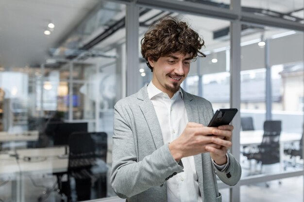 Successful businessman with beard standing near window man using phone happy boss typing message and