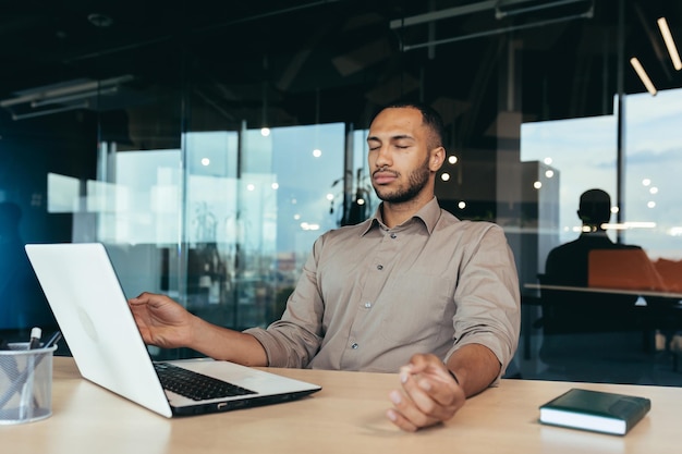 Successful businessman working inside modern office building man meditating with eyes closed in