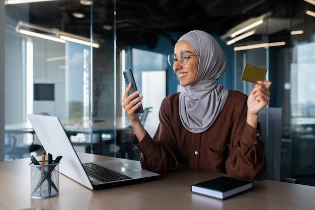 Successful businesswoman in hijab working inside office with laptop at workplace muslim woman