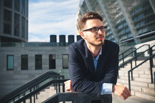 Successful caucasian businessman stand on stairs in modern city.