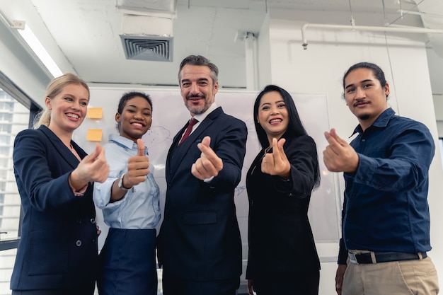 Successful cheerful business people group of multiracial business team with mini heart and smiling posing