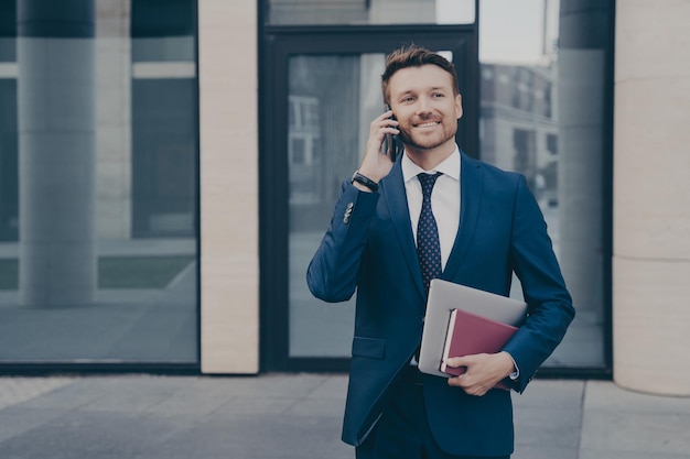 Successful and confident business owner talking on phone with his employee outdoors