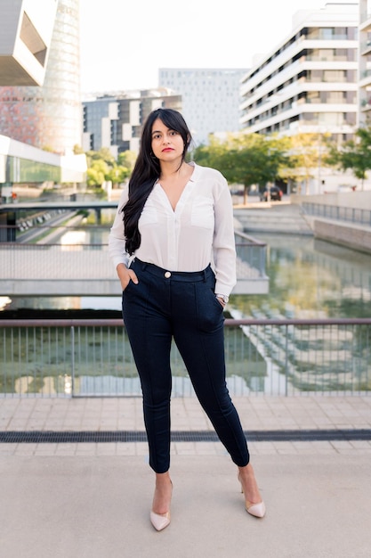 Successful curvy businesswoman looking serious at the camera in the financial district of the city, concept of entrepreneur and urban lifestyle