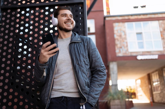 Successful european male freelancer listening to music with headphones outdoors