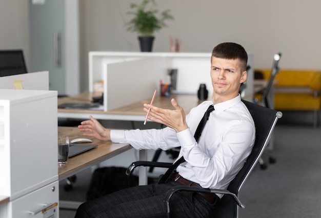 Successful happy business man sitting at a desk in the office and uses a laptop