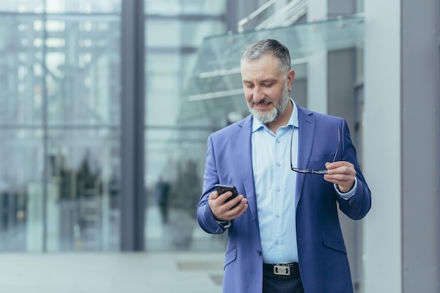 Successful and happy senior grayhaired businessman investor walking outside office building man