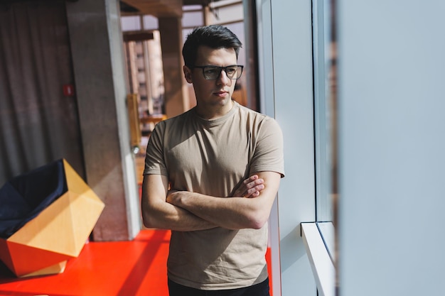 Successful male entrepreneur in the office standing near the window during a working day in the company a successful corporate boss feels good from a rich lifestyle