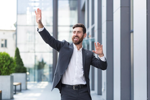 Successful male freelancer in a business suit dances near the office celebrates a winning deal, and a good end to the working day