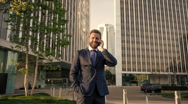 Successful man in formalwear speaking on phone outside the office negotiation