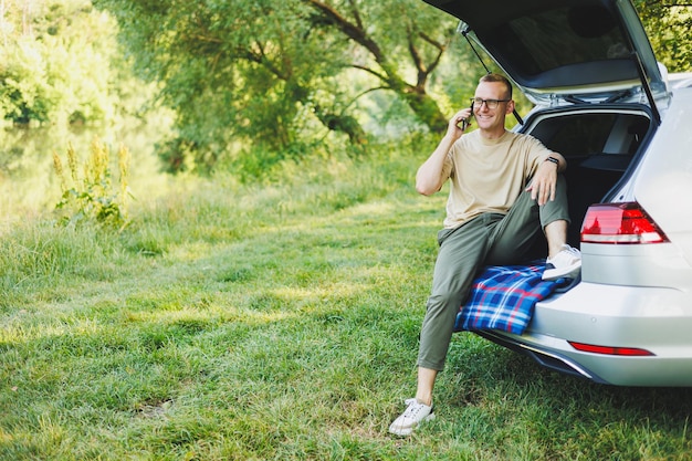 Successful man working outdoors from his car sitting in the trunk and looking at the laptop Online remote worker lifestyle concept Copy space