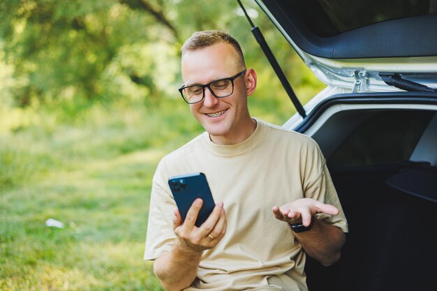 Successful man working outdoors from his car sitting in the trunk and looking at the laptop Online remote worker lifestyle concept Copy space