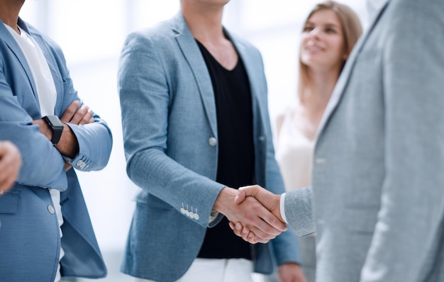 Successful managers shaking hands after closing deal in office