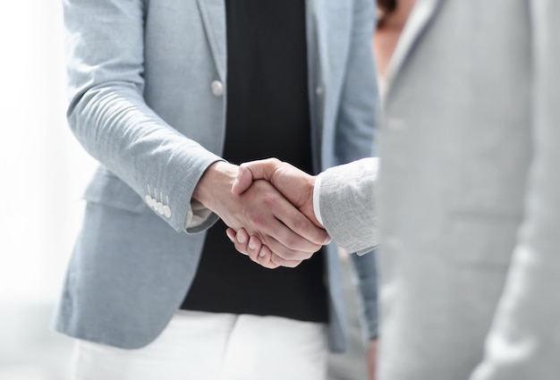 Successful managers shaking hands after closing deal in office