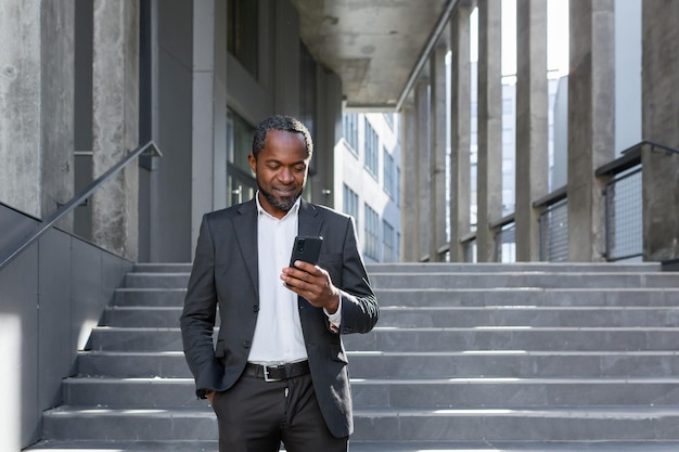 A successful mature african american man in a business suit is walking outside an office building