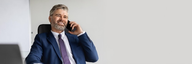 Successful mature businessman in suit talking on mobile phone at office handsome middle aged male