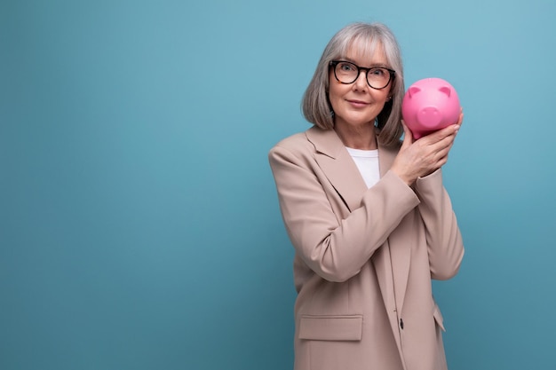 Successful middleaged woman with a piggy bank of money on a bright background with copy space