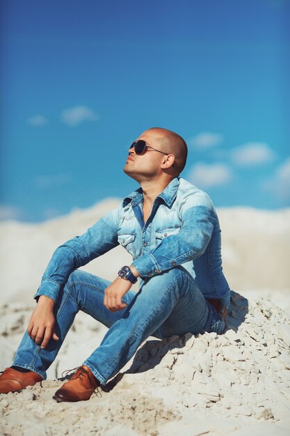 Successful person sitting on the sand at sunset