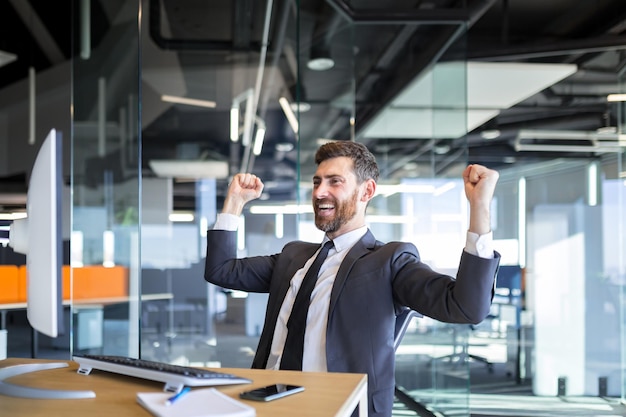 Successful seo man, boss business man, celebrates victory by working on computer in modern office