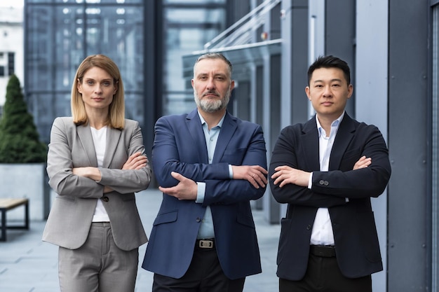 Successful and serious diverse team of three business people man and woman focused looking at camera