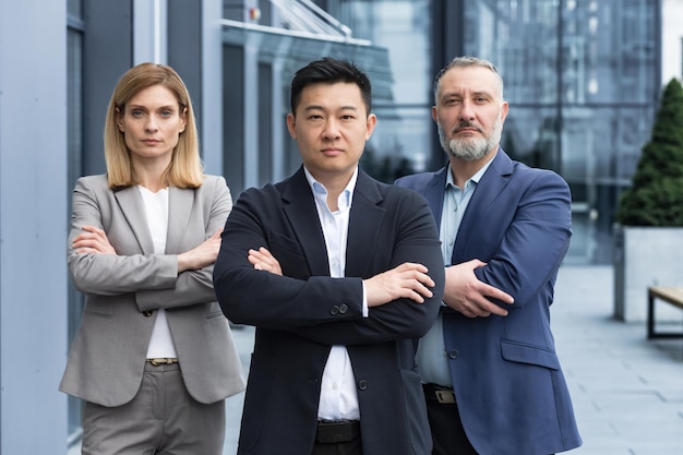 Successful and serious diverse team of three business people man and woman focused looking at camera