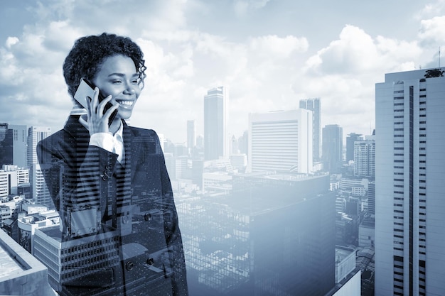 Successful smiling black African American business woman in suit pensively talking phone Bangkok cityscape The concept of consultants as problem solvers Double exposure