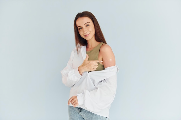 Successful vaccination Young woman in white clothes sitting indoors against white background