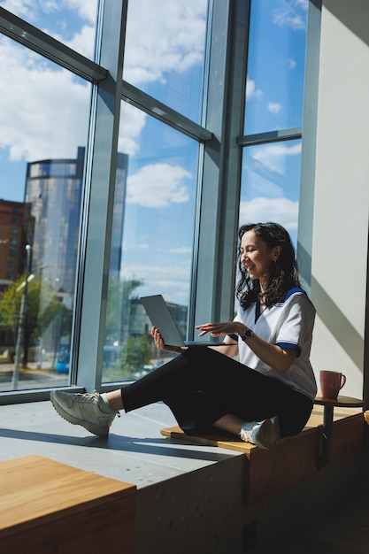 Successful woman looking for creative ideas on laptop during work process Positive girl student with reading business news on netbook while sitting in modern workspace