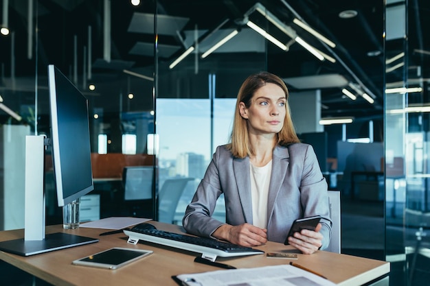 Successful woman working in a modern office on a computer businesswoman uses the phone social networks online browsing