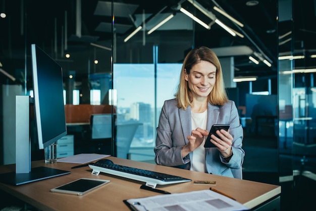 Successful woman working in a modern office on a computer businesswoman uses the phone social networks online browsing