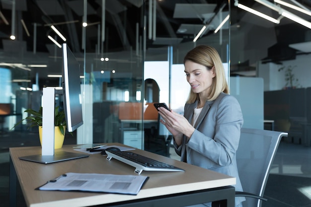 Successful woman working in a modern office on a computer businesswoman uses the phone social networks online browsing