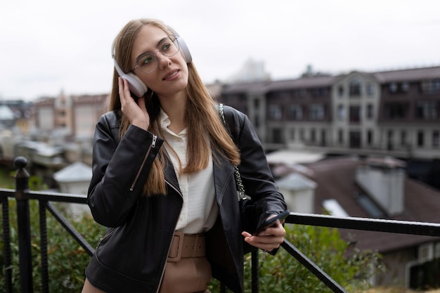 Successful young adult female student listening to music with headphones in urban environment