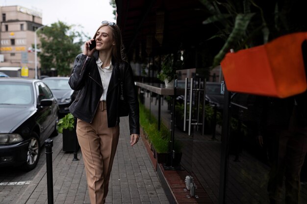 Successful young adult female student walking around the city and talking on the phone