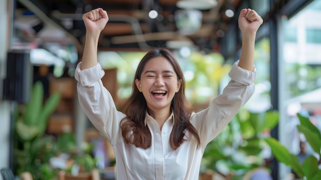 A successful young Asian businesswoman achieves her goals excitedly raising