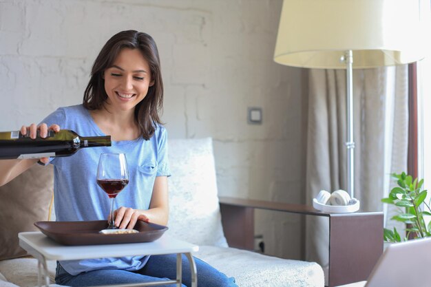 Successful young beautiful woman sitting on a sofa in the living room drinking red wine