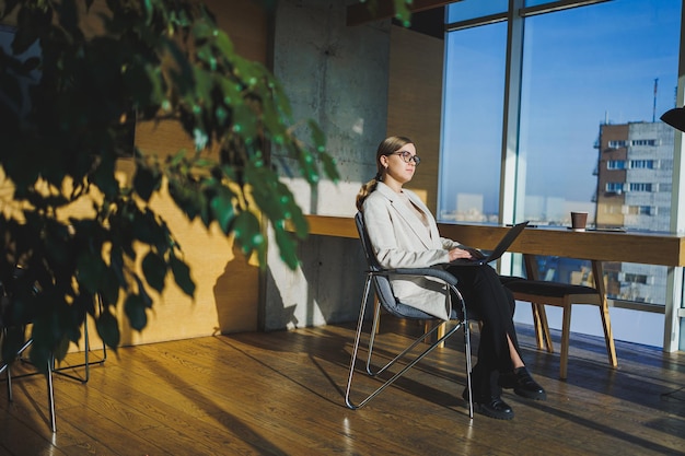 Successful young business woman in glasses with laptop in office Business woman sending email message and working on laptop Young business woman sitting at workplace